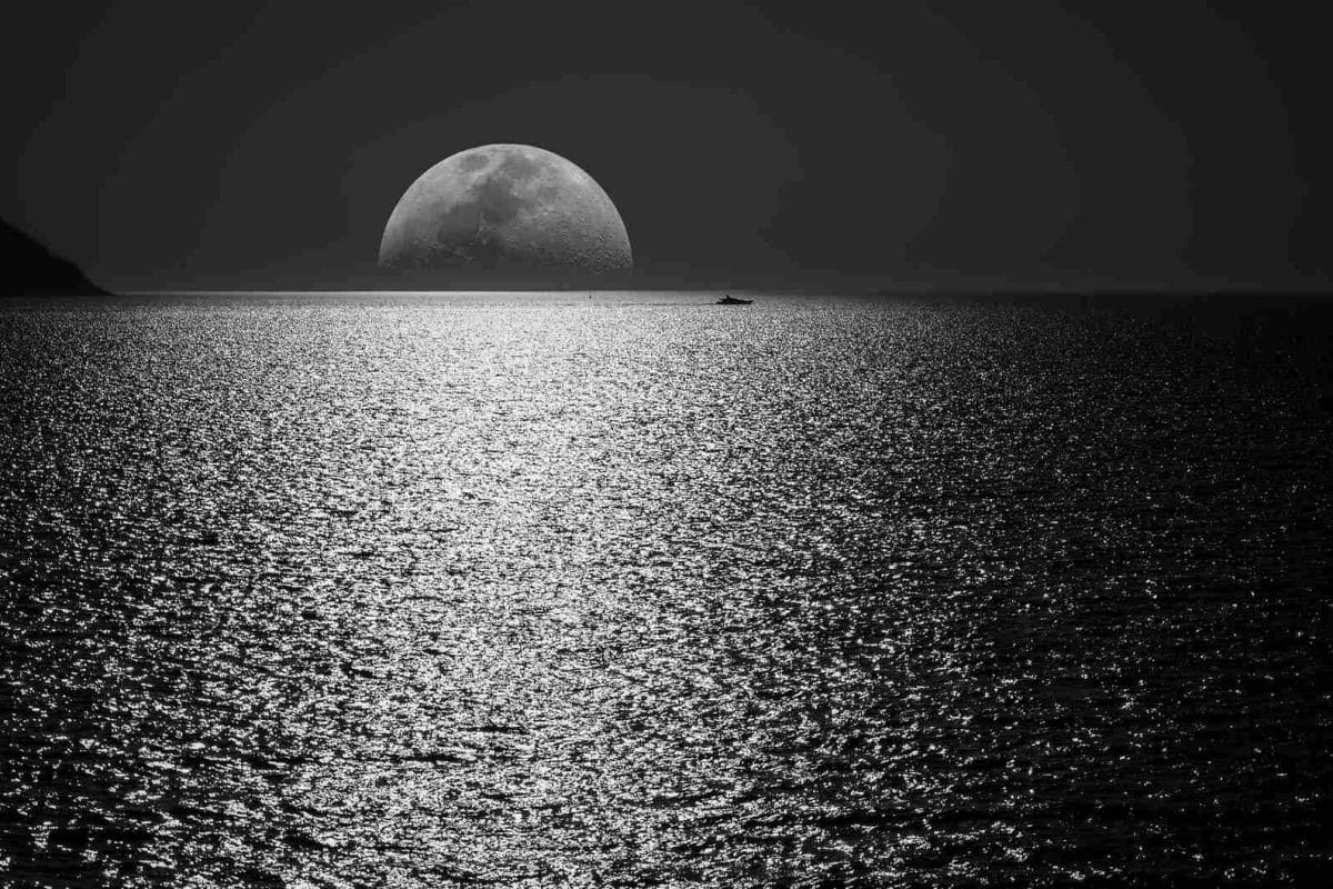 white and black moon with black skies and body of water photography during night time