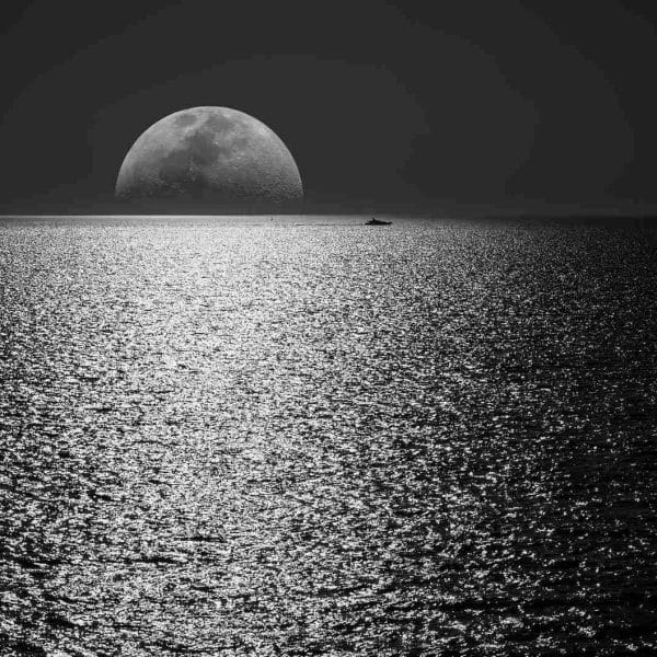 white and black moon with black skies and body of water photography during night time